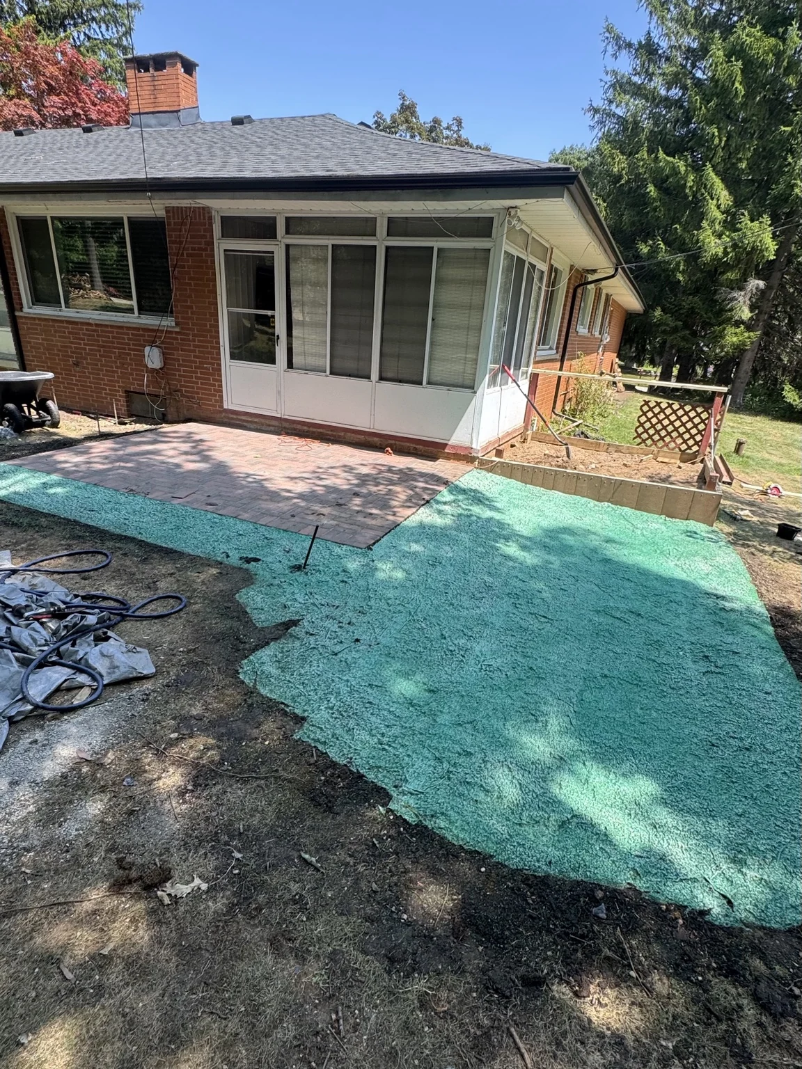 Completed paver patio beside a brick home and enclosed porch