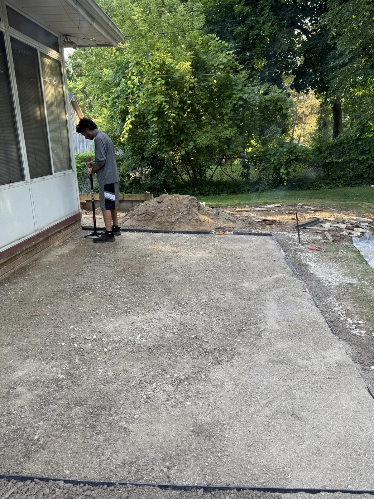 Worker compacting a paver patio base