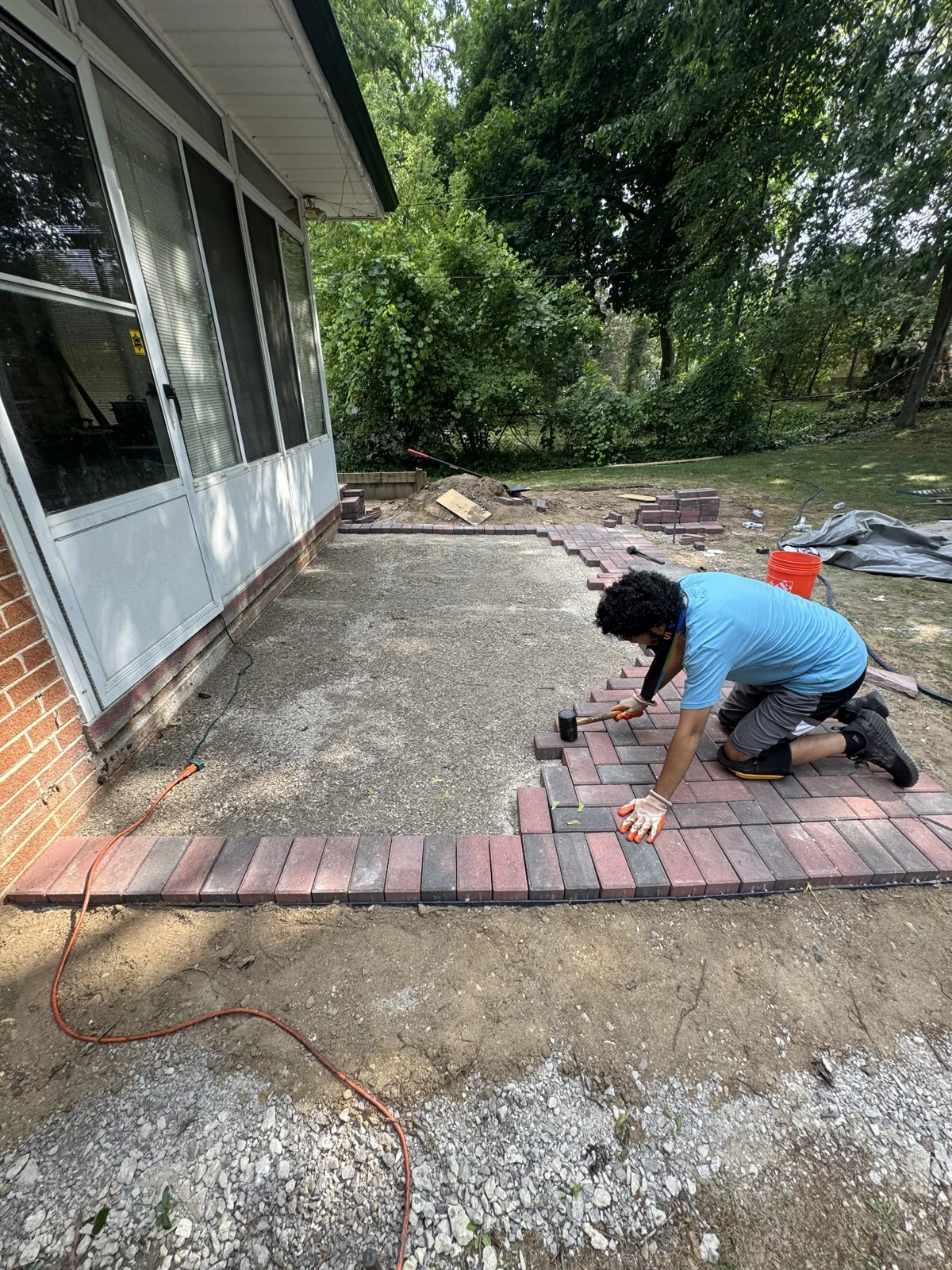 Worker laying pavers around the prepared patio base