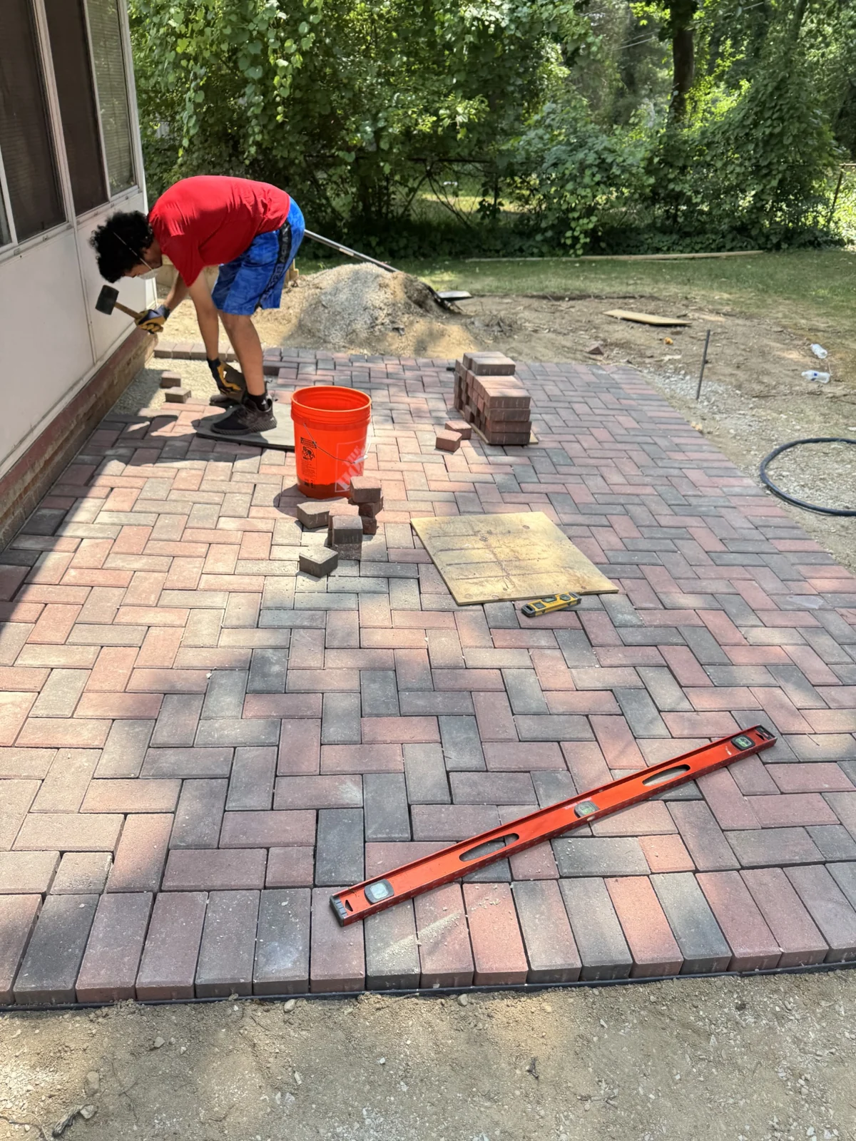 Worker fitting pavers beside a home